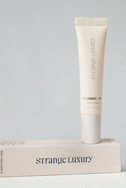 Tube of Strange Luxury skincare product on a matching box against a gray background.