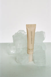 Skincare tube on a textured white surface with a light gray background.