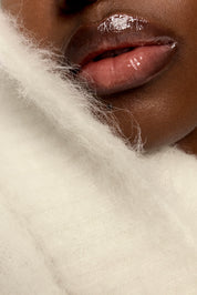 Close-up of a person's lips with glossy lipstick on a white background