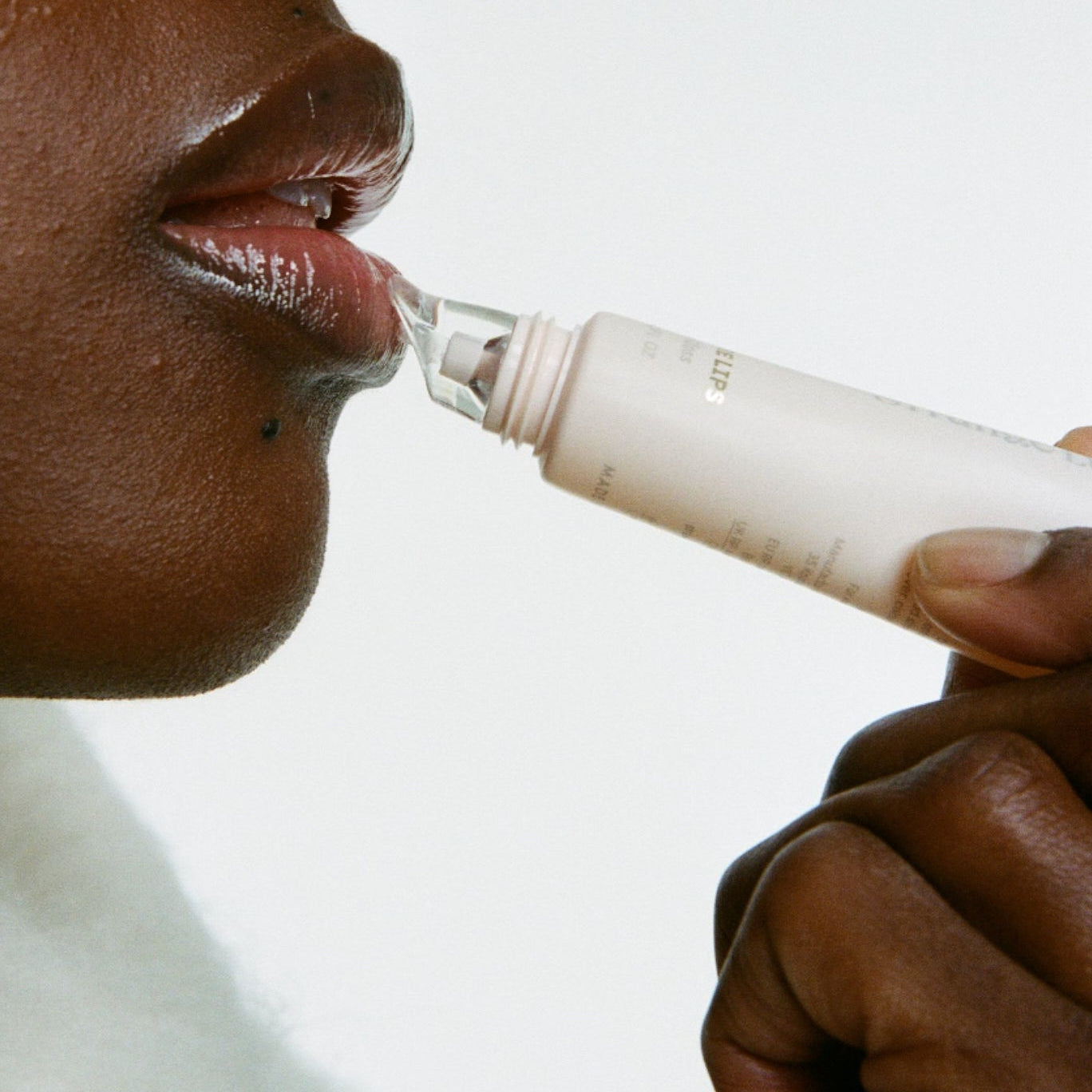 Person using lip gloss on a white background.