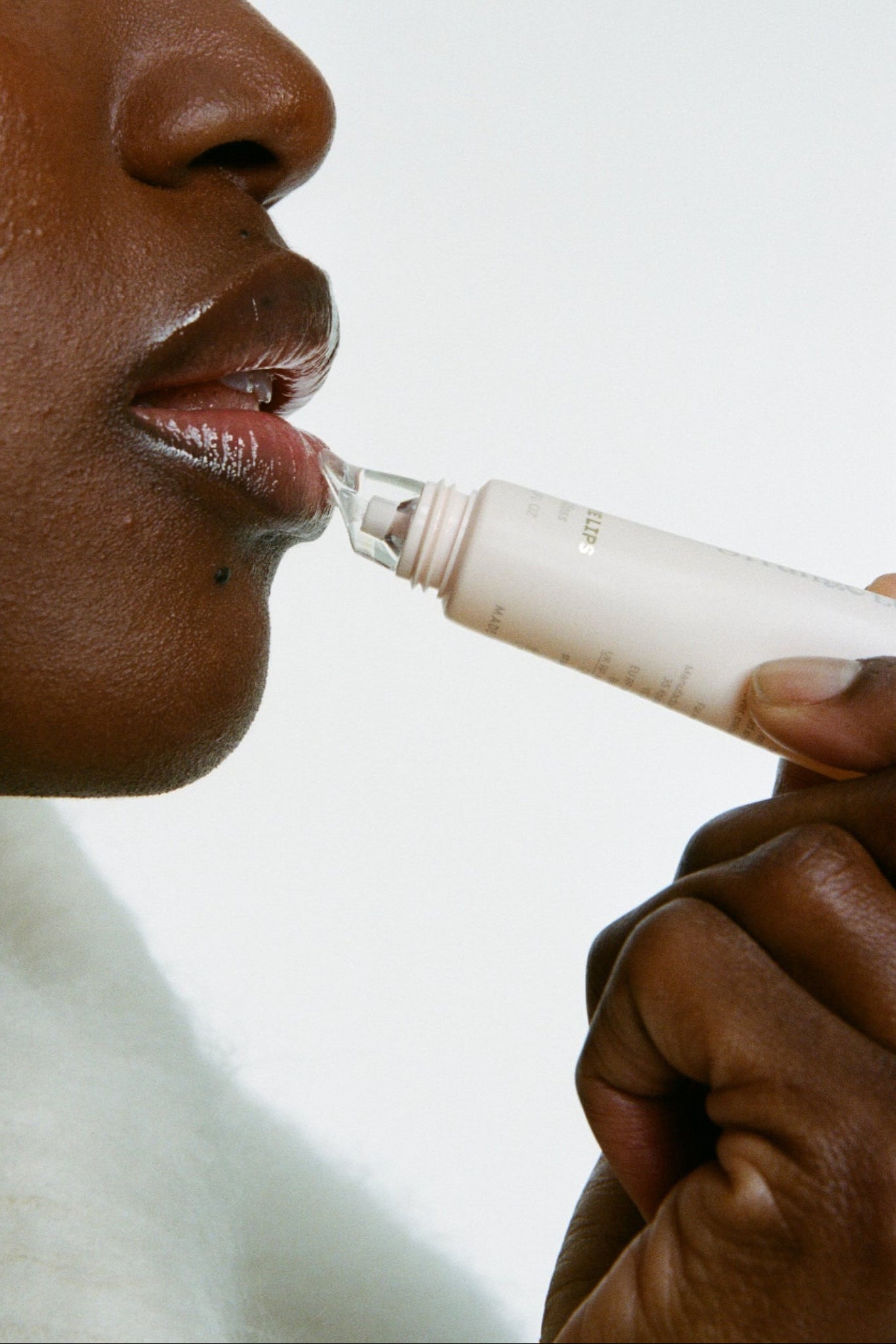 Person using lip gloss on a white background.