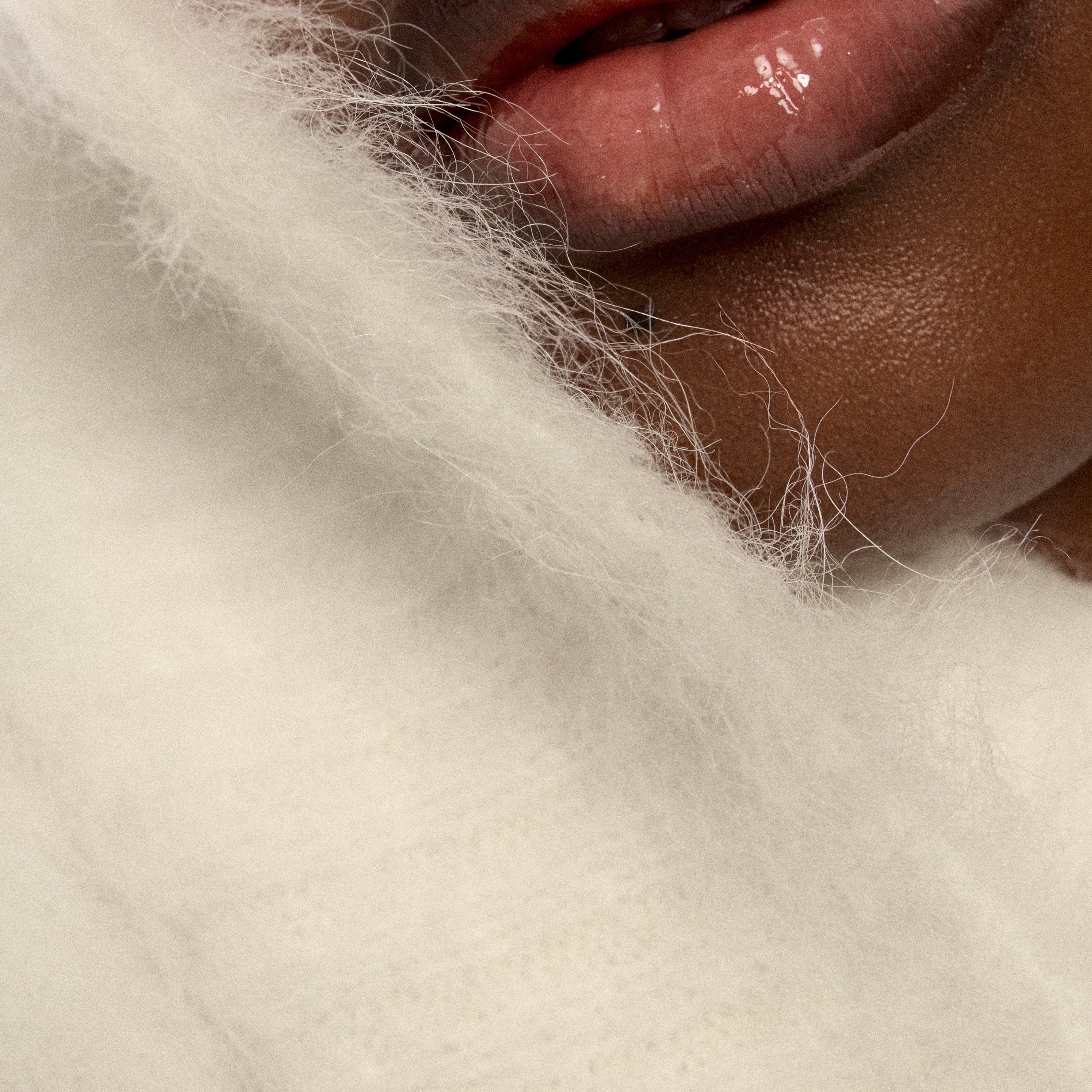 Close-up of a person's lips with a white cashmere background.