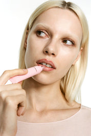 Woman applying lip balm with a white background.