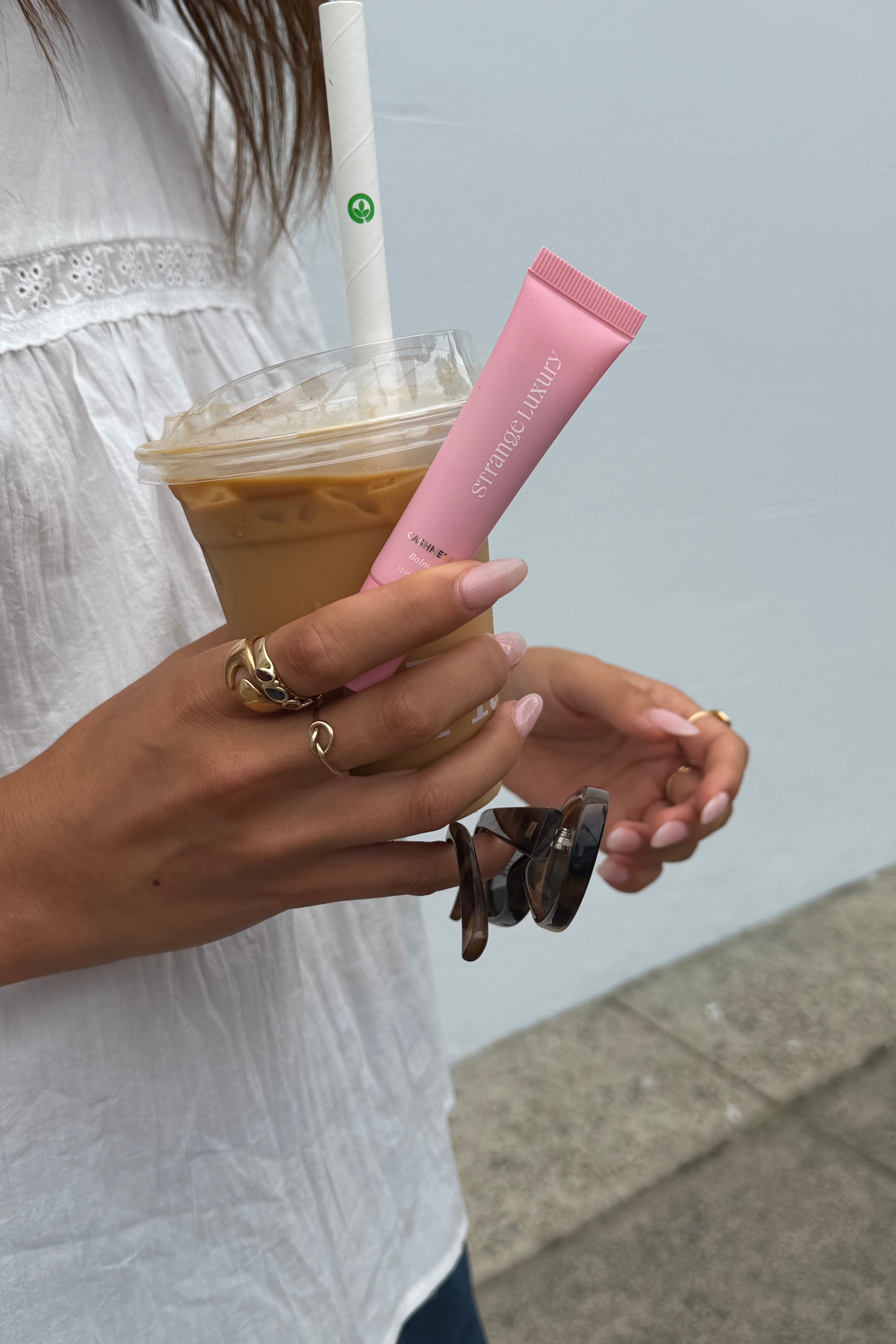 Hand holding a pink lip balm with a blurred background.