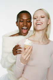 Two women holding a cupcake against a white background.
