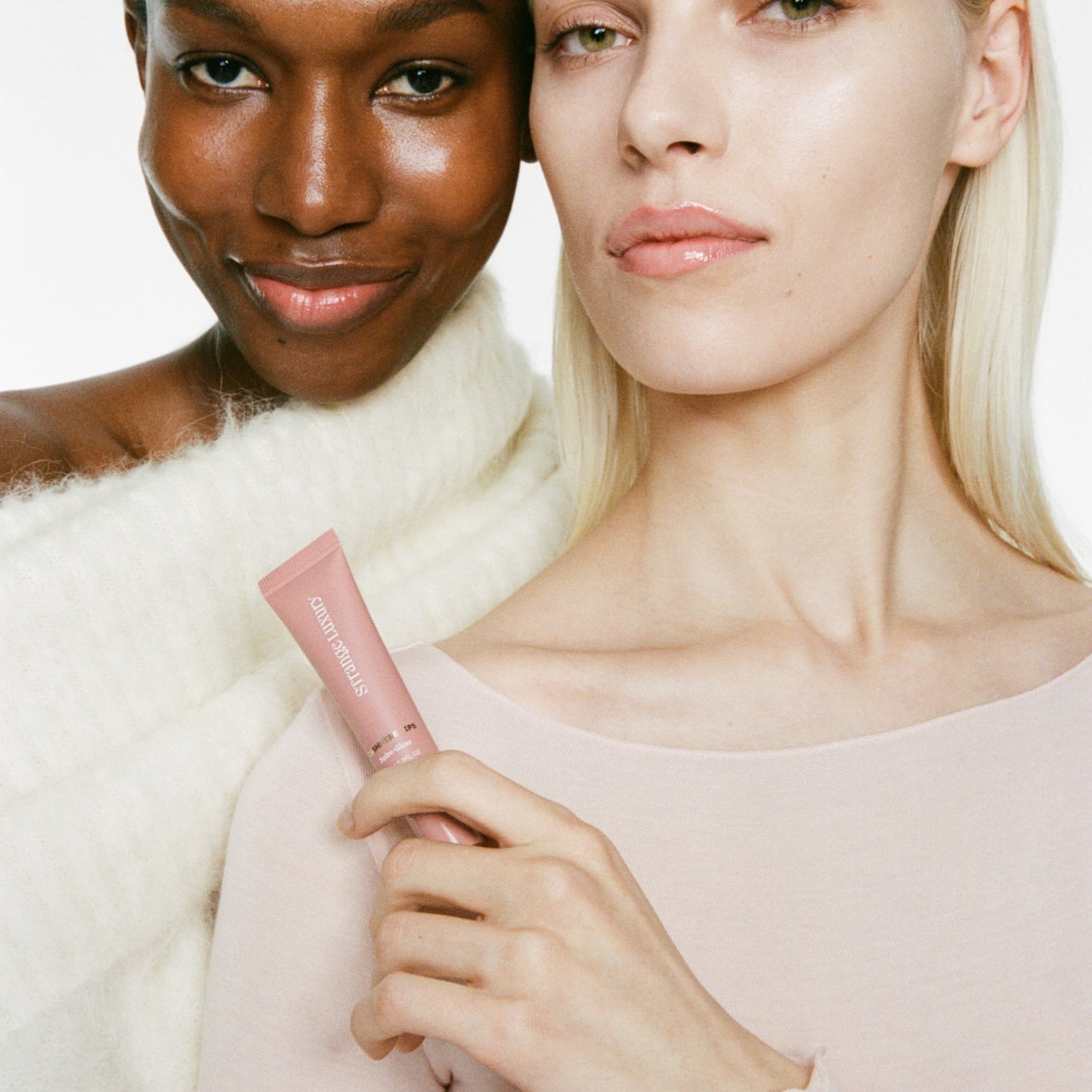 Two women holding a pink product against a white background.