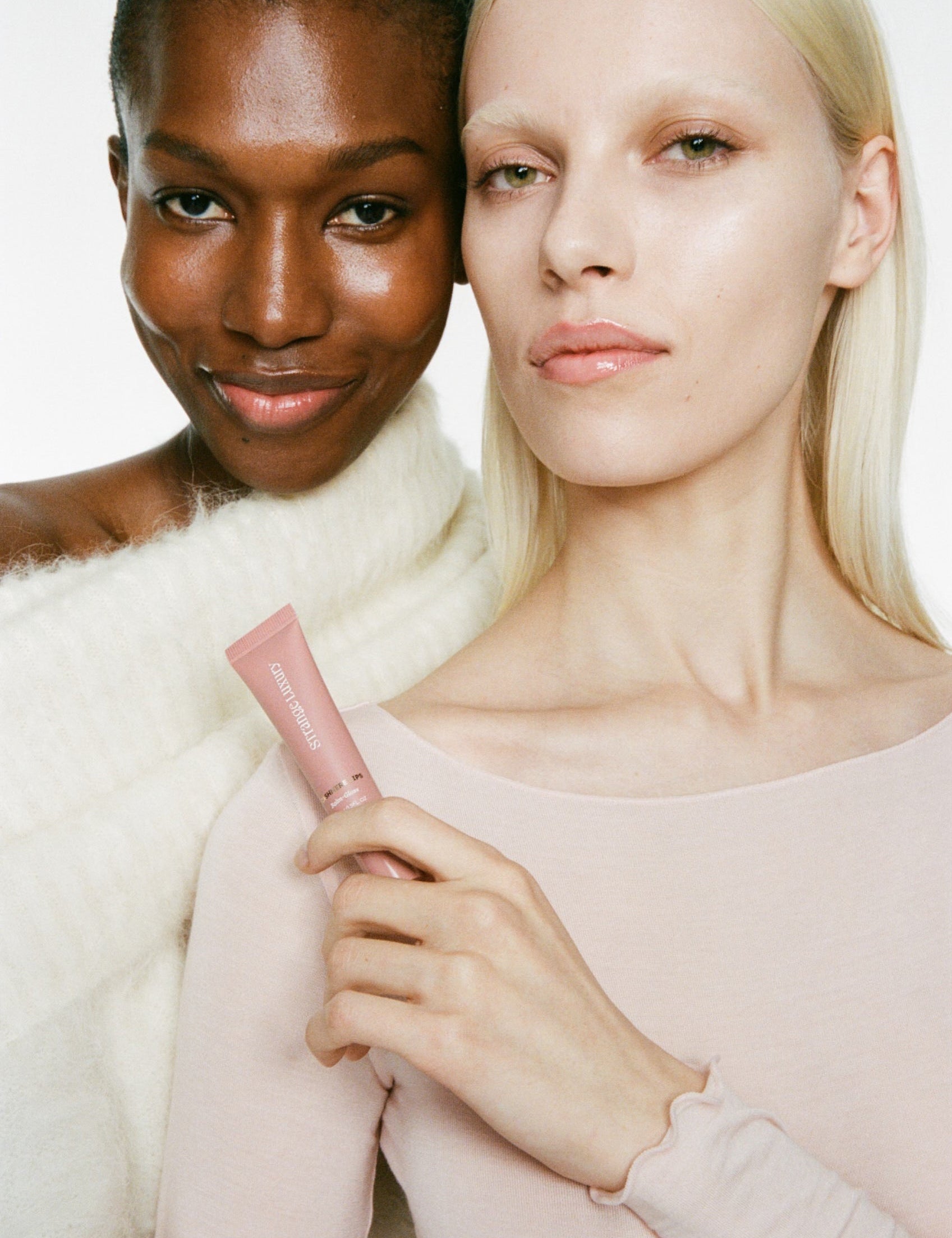 Two women holding a pink product against a white background.