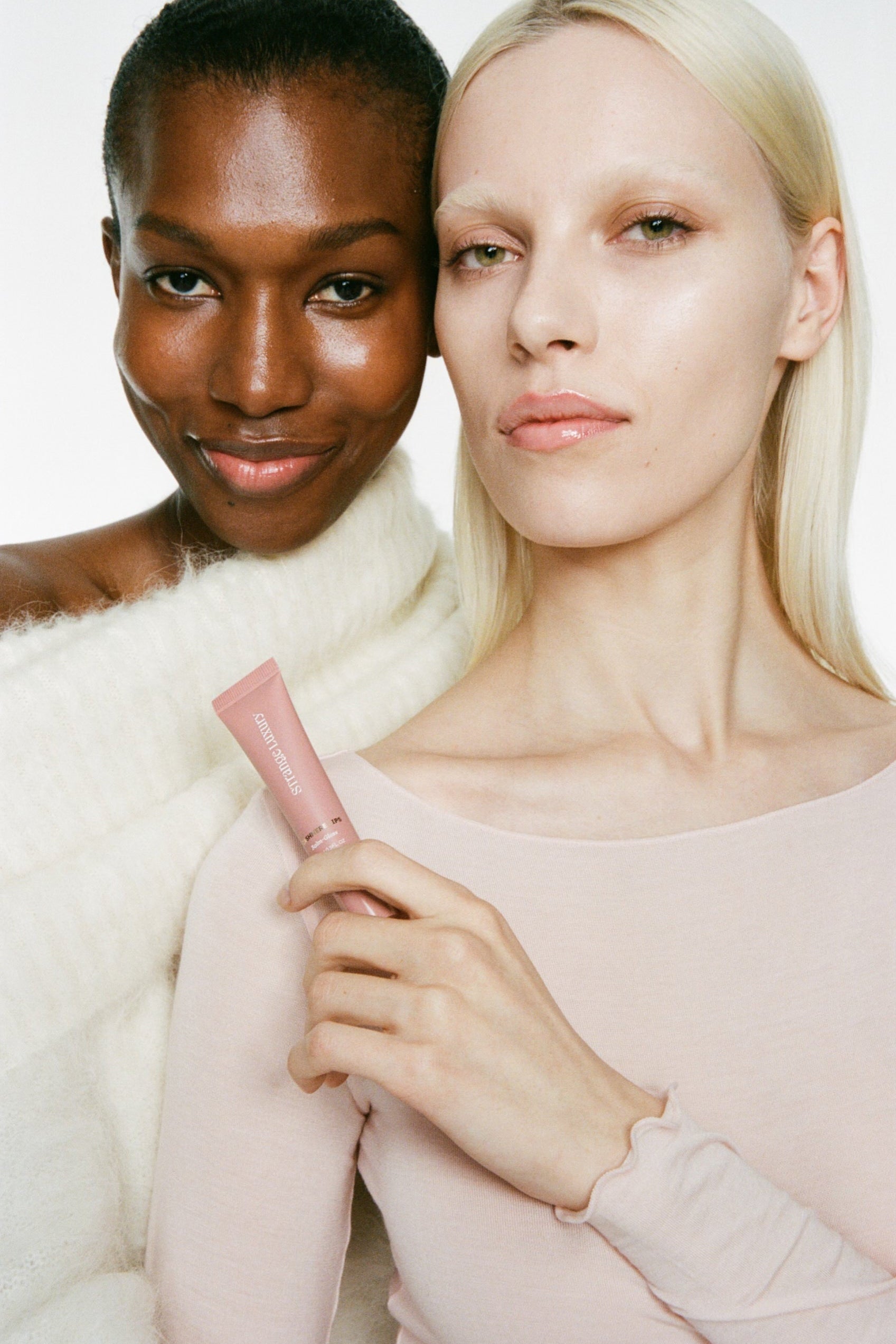 Two women holding a pink product against a white background.