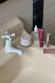 Bathroom sink with skincare products and a faucet.