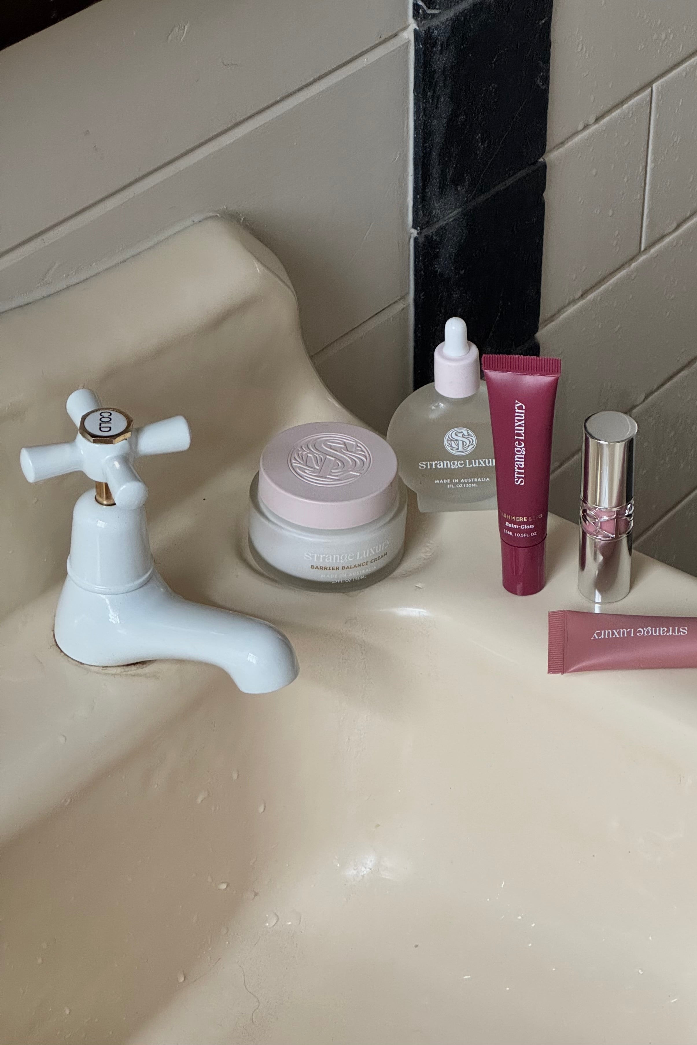 Bathroom sink with skincare products and a faucet.