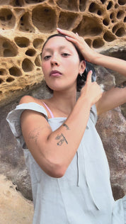 Amber brushing hair and applying lip gloss against stone background.